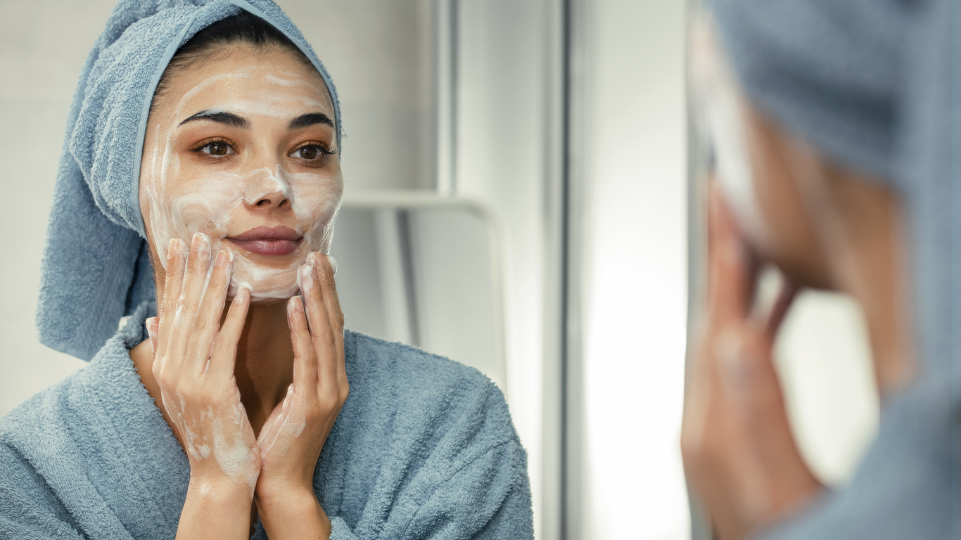 Woman applying skincare products to her face.