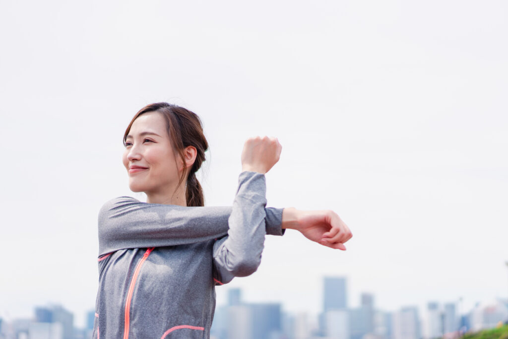 Young woman stretching outdoors with a smile
