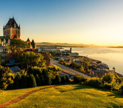 A beautiful view of the Chateau Frontenac surrounded by greenery in Quebec, Canada at sunrise